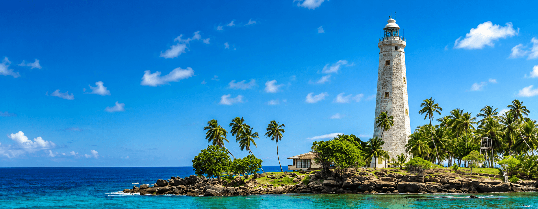 White lighthouse on a tropical rocky coast in Sri Lanka